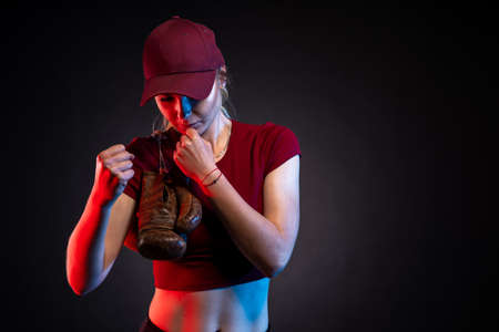 portrait of woman with old boxing gloves on black background, copy space