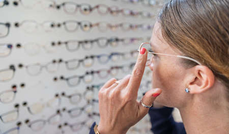 woman chooses and tries glasses in optics store. copy spaceの写真素材