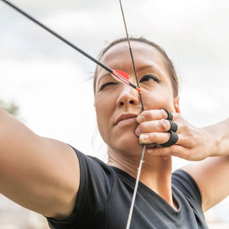 attractive woman on archery, focuses eye target for arrow from bowの写真素材