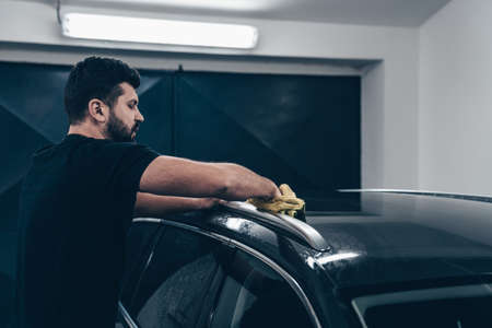 man cleans the car body with a towel. auto careの写真素材