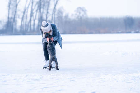 ice skating on the ice of a frozen lake young attractive woman with dogの写真素材