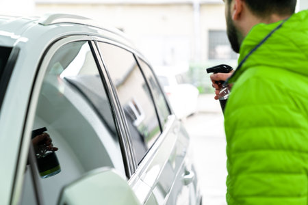 man cleans the car glass with a sprayer. auto careの写真素材