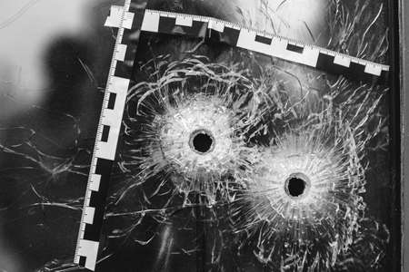 bullet holes in a glass shop window marked with a police tapeの写真素材