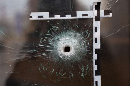 bullet holes in a glass shop window marked with a police tape