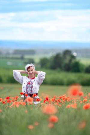 woman in Ukrainian national dress on a flowering poppy fieldの写真素材