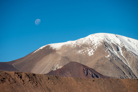 snowy Andes hills with moon in the skyの写真素材
