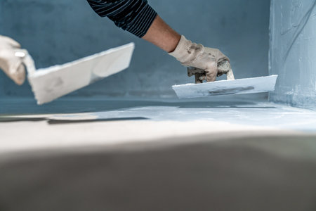 work with trowel on floor and wall in new room in buildingの写真素材