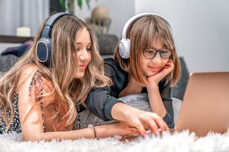 children with wireless headphones on their heads enjoy internet entertainment online on a laptop at...