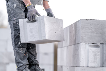 a mason builds the wall of a house from concrete bricks