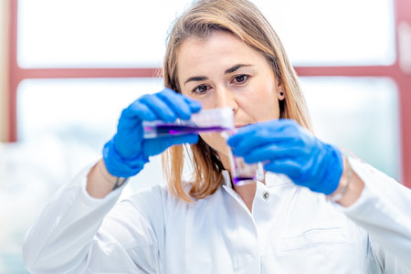 young attractive female scientist examines chemical samples of substances and drugs in a research...