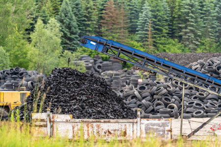 recycling and processing of old tires, crushed rubber go on a conveyor belt to a containerの写真素材