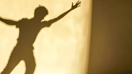 Shadow of a man raising his arms on a wallの素材