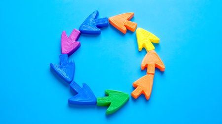 Colorful clay arrows forming a circle on blue backgroundの素材
