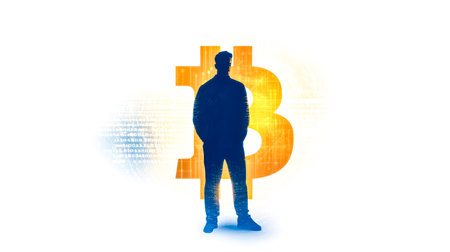 Mysterious silhouette standing in front of bitcoin symbolの素材