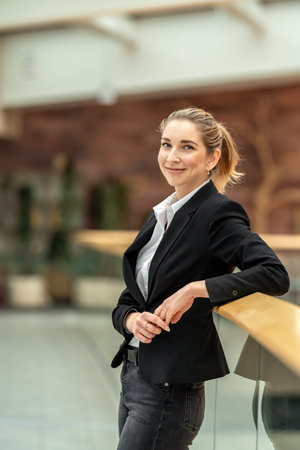 Businesswoman leaning on railing in modern office buildingの写真素材