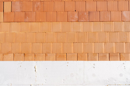 Brick wall meeting white insulation layer during building construction