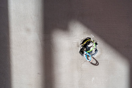 Electrical wiring protruding from hole in concrete wall during renovation