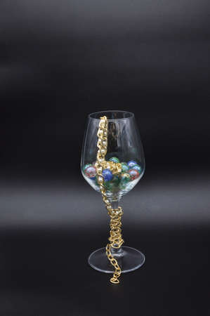 wine glass filled with colored glass marbles and pearl necklaceの写真素材