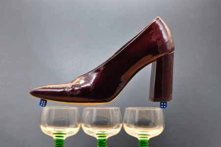 composition with female shoe balanced on dice resting on glasses. Conceptual photo about the dangers...