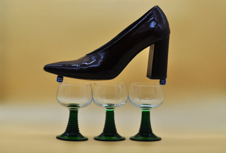 composition with female shoe balanced on dice resting on glasses. Conceptual photo about the dangers of gambling.の写真素材