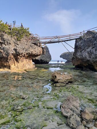 A bridge connecting two rocks on the beachの写真素材