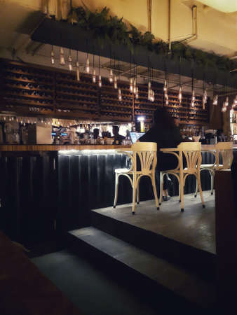 Inside view of a wine shop. Jakarta, Indonesia - July 18, 2019: Unidentified woman sitting and using a laptop computer in a wine house.のeditorial素材