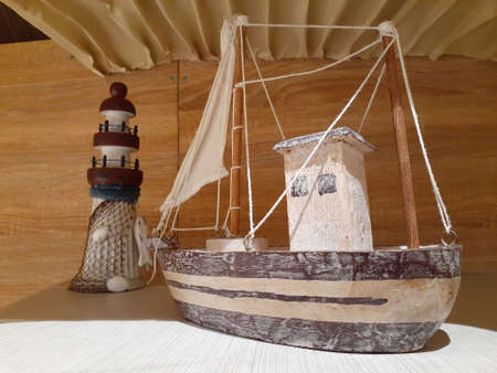 Close up of a wooden toy ship adjacent to a lighthouse.の写真素材