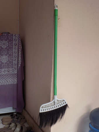 A floor broom hanging on the wall of the house.の写真素材