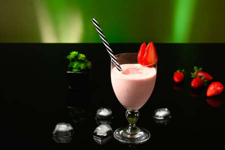 strawberry drink with champagne in a glass on a black glass tableの写真素材