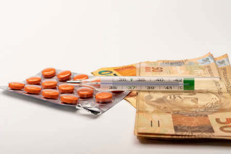 pills palette and thermometer with Brazilian money