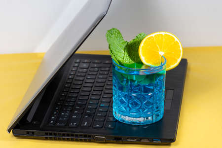 blue cocktail glass on laptop keyboardの写真素材