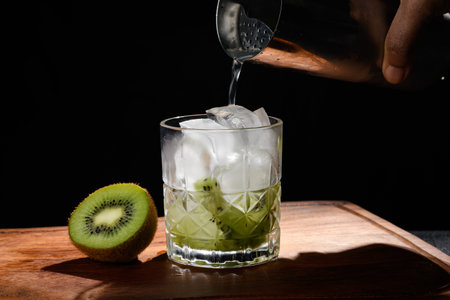 whiskey with ice and kiwi on a black backgroundの写真素材