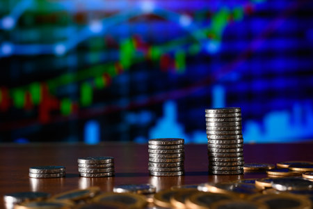 Stacks of coins on the table with stock market graph background.の写真素材