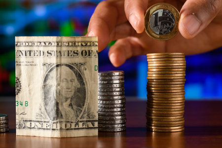 Man's hand putting a coin to stack of coins and dollar billsの写真素材