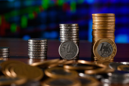 Stack of coins on table with stock market chart background. Business and finance concept.の写真素材