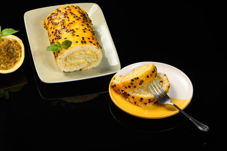 Piece of passion fruit roll with passion fruit seeds on a black background.の写真素材