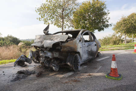 Wrecked and burning car on the roadの写真素材