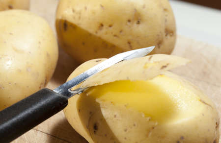 Close-up of a person peeling potatoes with a peelerの写真素材