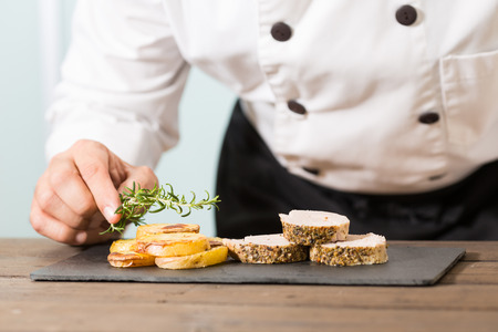 Chef decorating a pork tenderloin with potatoesの写真素材