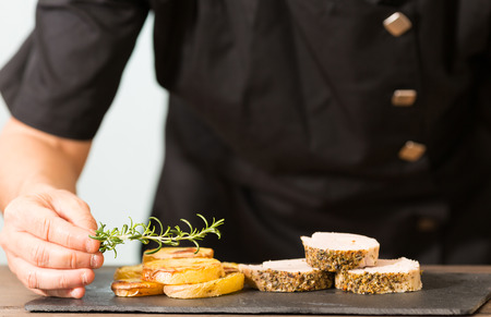 Chef decorating a pork tenderloin with potatoesの写真素材