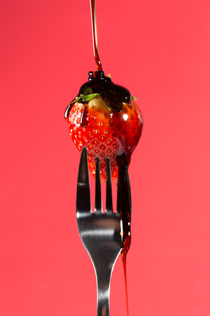 Strawberry with caramel syrup on a forkの写真素材