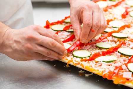 Chef preparing a delicious pizza with vegetablesの写真素材