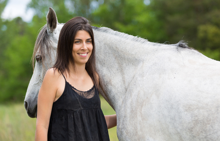 Happy young woman with her horse and strollingの写真素材