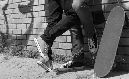 Couple of guys with his skateboard next to a wall with graffiti