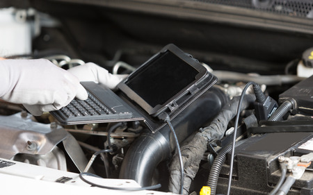 Car mechanic with a tablet making a diagnosis engine
