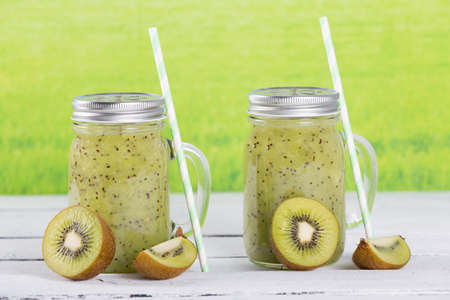 Natural kiwi juice in glass pitcher with strawsの写真素材