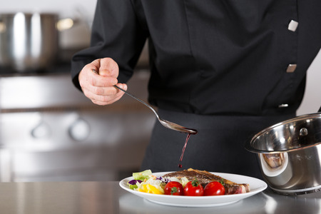 Chef finishing her plate and almost ready to serve at the tableの写真素材