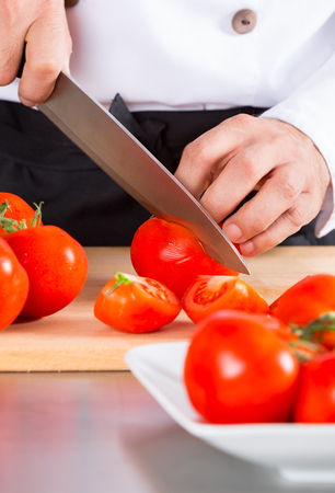 Chef cutting some delicious and healthy red tomatoesの写真素材