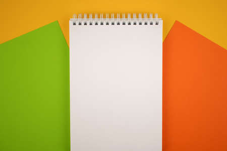 Notepad with a white sheet on a yellow background. Man's hand tries to write.