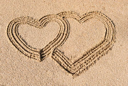 two hearts drawn in the sand as a symbol of loveの写真素材